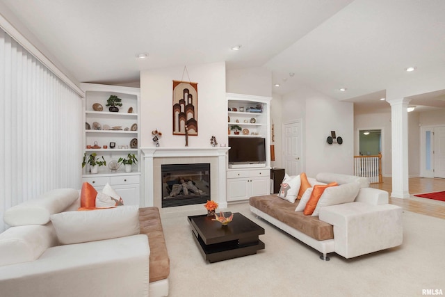 living area with decorative columns, built in features, vaulted ceiling, and a tile fireplace