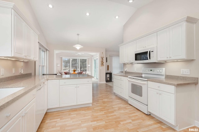 kitchen featuring white appliances, light wood-style flooring, a peninsula, vaulted ceiling, and white cabinetry