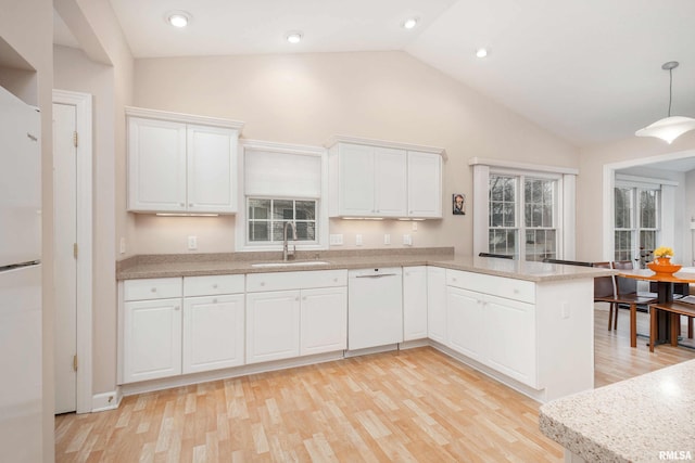 kitchen featuring white cabinets, a sink, light wood-type flooring, white appliances, and a peninsula