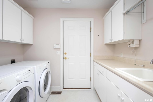 laundry area with cabinet space, washing machine and dryer, visible vents, and a sink