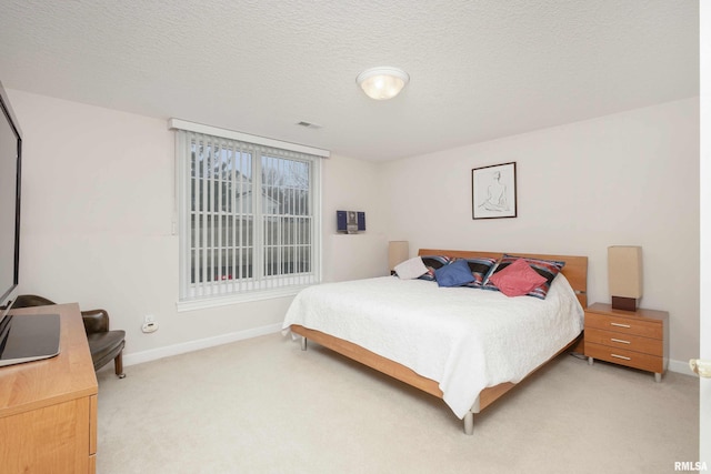 bedroom featuring light carpet, baseboards, and a textured ceiling