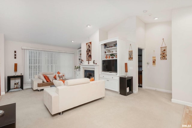 living area with recessed lighting, a glass covered fireplace, light carpet, vaulted ceiling, and baseboards