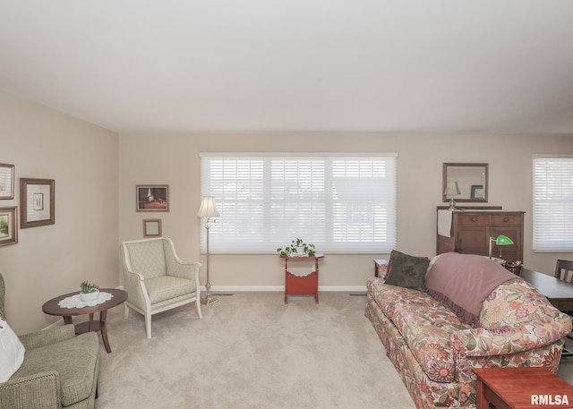 living area with a healthy amount of sunlight, light carpet, and baseboards