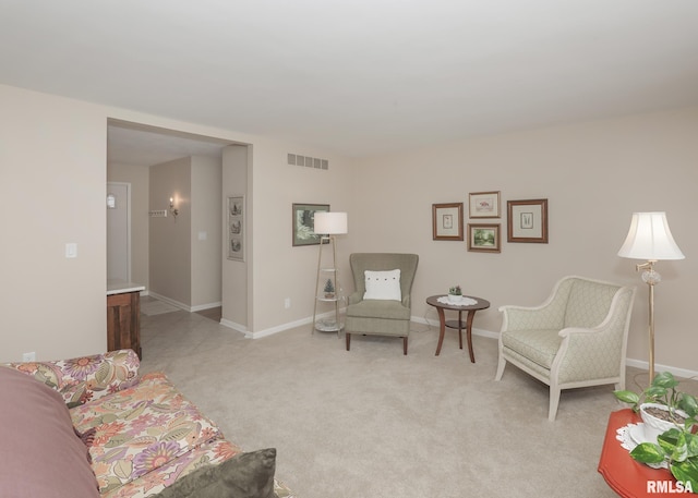 living area with baseboards, visible vents, and light colored carpet