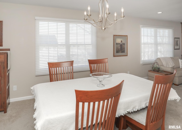 dining space featuring light carpet, baseboards, and a chandelier