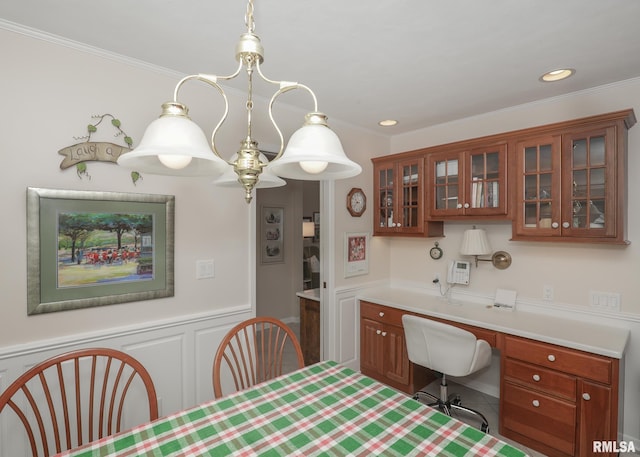 kitchen featuring glass insert cabinets, light countertops, crown molding, and built in desk