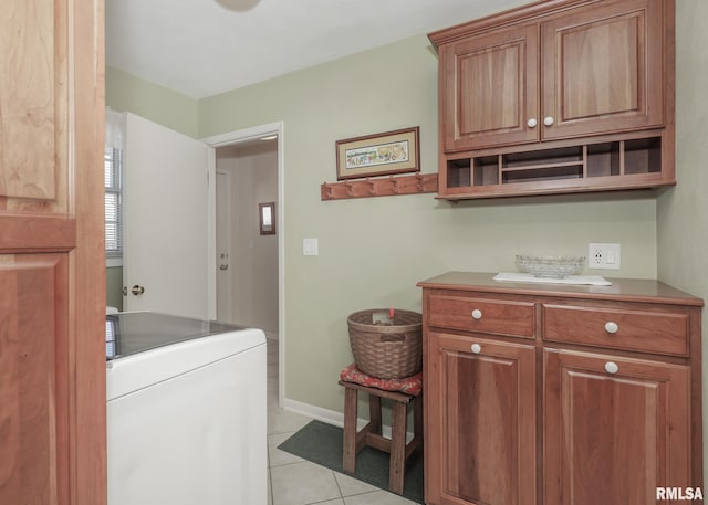 clothes washing area with light tile patterned flooring, cabinet space, washer / dryer, and baseboards