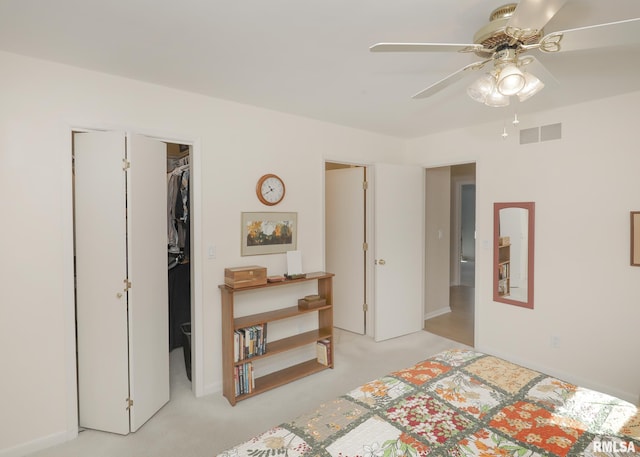 bedroom featuring a walk in closet, a closet, visible vents, and light carpet