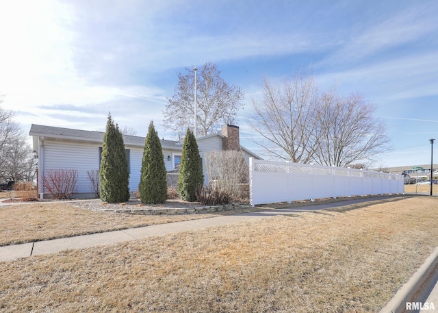 view of side of property with a chimney and fence