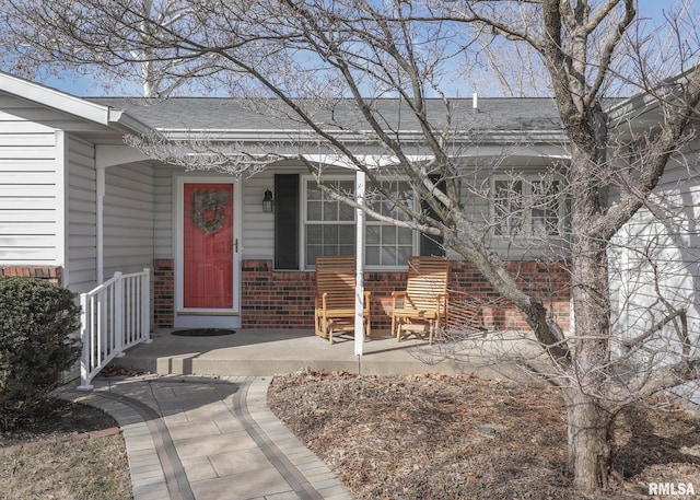 entrance to property with brick siding and roof with shingles