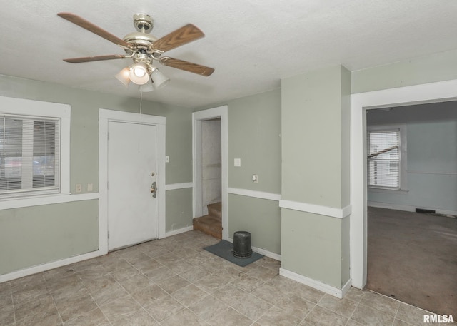 entryway with baseboards, visible vents, stairway, and a ceiling fan