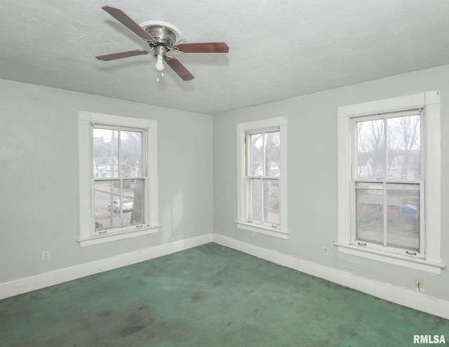 carpeted spare room featuring a healthy amount of sunlight, a textured ceiling, and baseboards