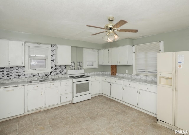 kitchen with white appliances, light countertops, a sink, and white cabinets