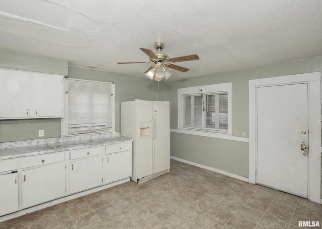 kitchen with white fridge with ice dispenser, white cabinets, light countertops, and ceiling fan