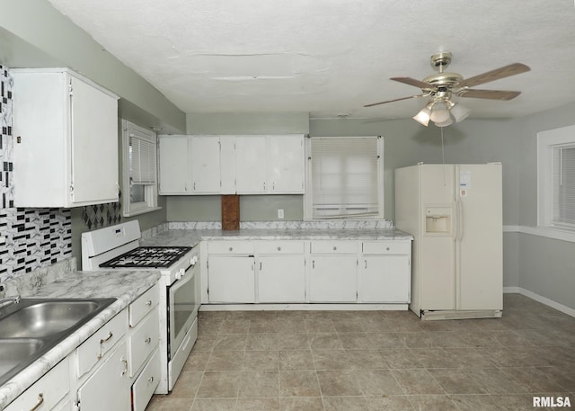 kitchen featuring white appliances, white cabinets, and a sink