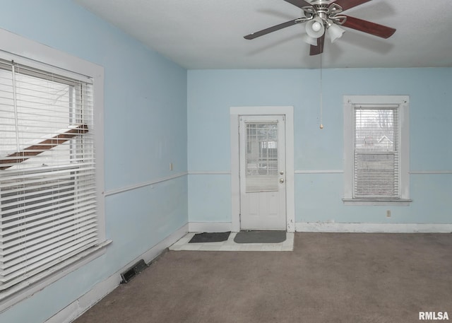 carpeted spare room with visible vents, baseboards, and ceiling fan