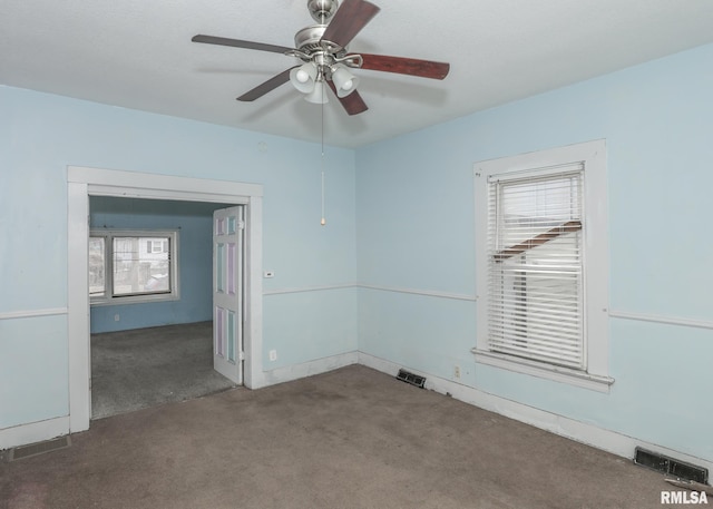 carpeted spare room featuring a ceiling fan and visible vents