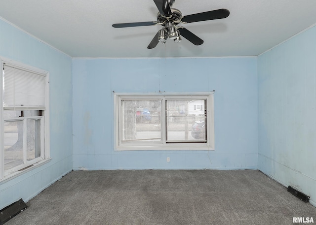 empty room featuring ornamental molding, carpet flooring, visible vents, and a ceiling fan