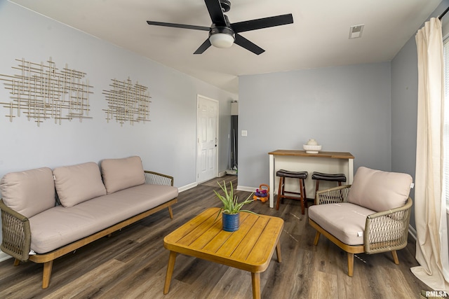 living room featuring visible vents, ceiling fan, baseboards, and wood finished floors