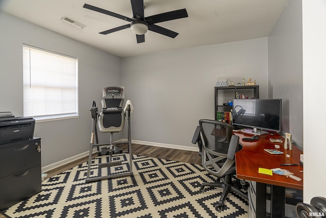 home office with a ceiling fan, visible vents, baseboards, and wood finished floors