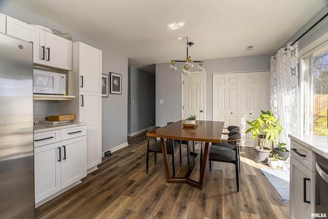 dining space with dark wood-style flooring, visible vents, baseboards, and an inviting chandelier