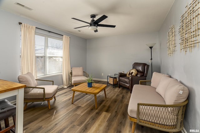 living area with baseboards, dark wood-type flooring, visible vents, and a ceiling fan