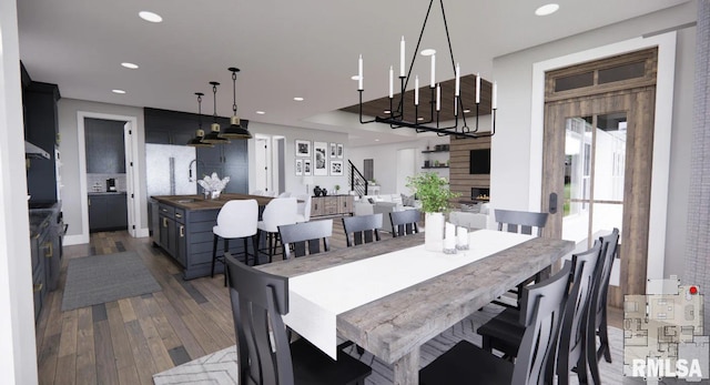 dining room with recessed lighting, a warm lit fireplace, dark wood-style flooring, and stairs