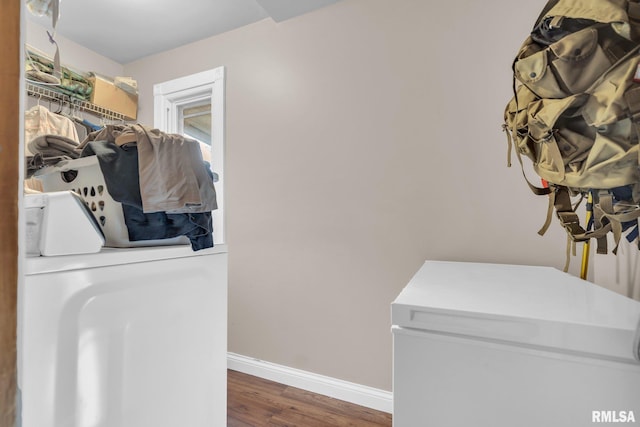 clothes washing area featuring laundry area, baseboards, washing machine and clothes dryer, and wood finished floors