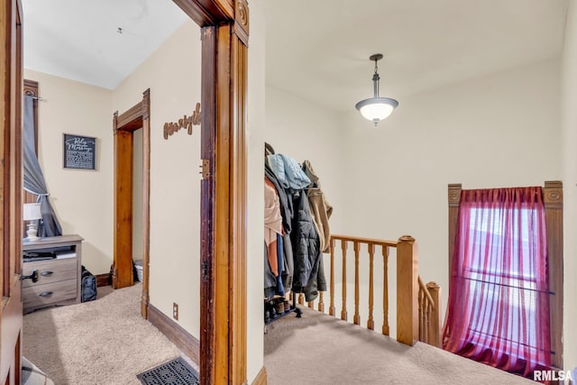 corridor featuring baseboards, carpet flooring, visible vents, and an upstairs landing