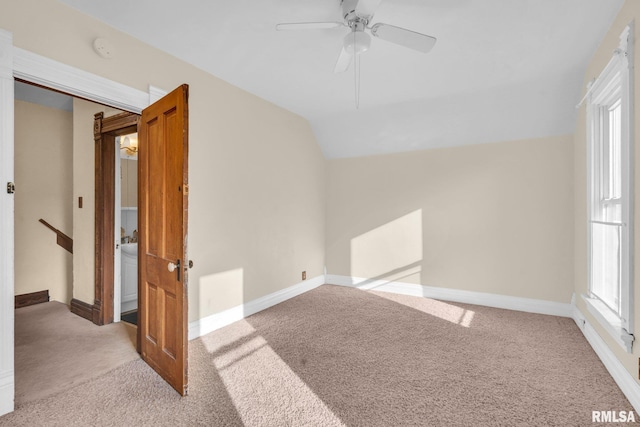 carpeted spare room featuring lofted ceiling, ceiling fan, and baseboards