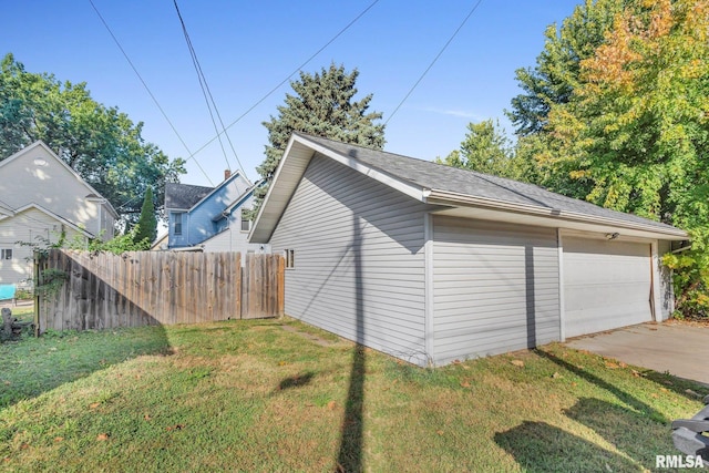 view of side of home featuring a garage, fence, an outbuilding, and a yard