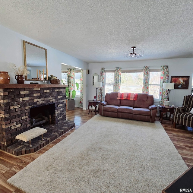 living room with a fireplace, a textured ceiling, and wood finished floors