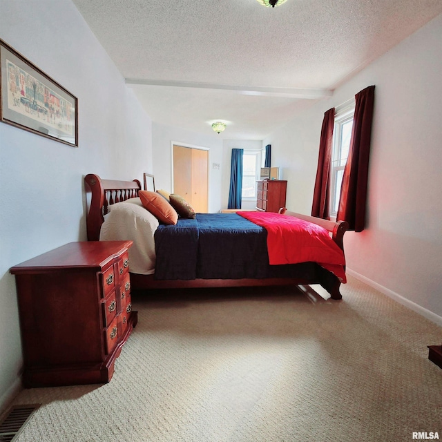 bedroom with carpet, visible vents, baseboards, and a textured ceiling