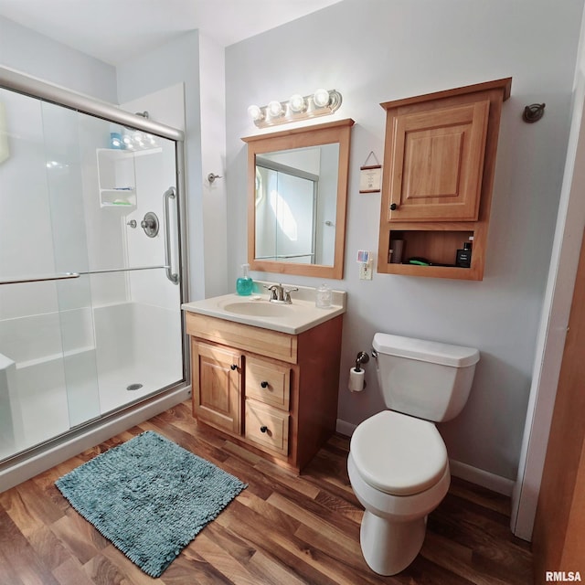 bathroom featuring a stall shower, baseboards, toilet, wood finished floors, and vanity