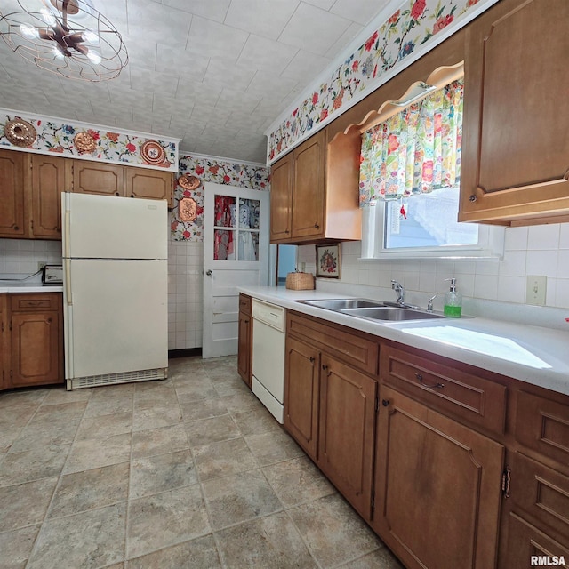 kitchen with brown cabinets, white appliances, light countertops, and a sink