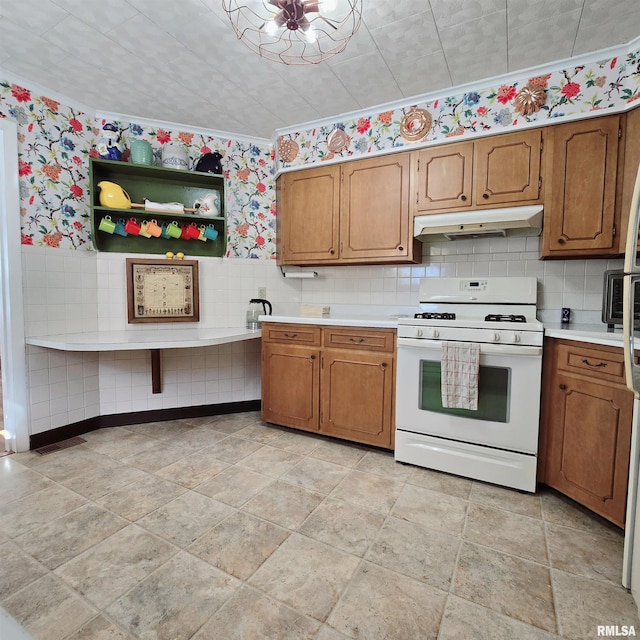 kitchen with under cabinet range hood, white range with gas cooktop, light countertops, brown cabinetry, and wallpapered walls