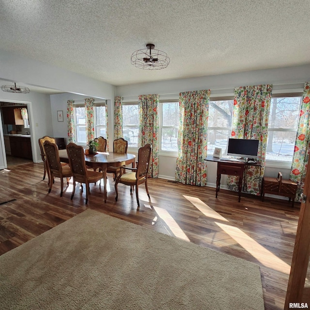 dining room featuring a textured ceiling, baseboards, and wood finished floors