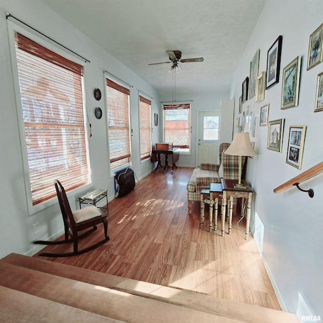 sitting room featuring baseboards, a textured ceiling, a ceiling fan, and wood finished floors