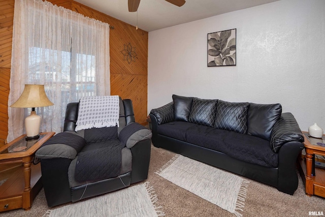 carpeted living room with wood walls and ceiling fan