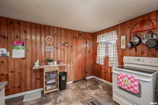 kitchen with visible vents, wood walls, white electric range oven, and baseboards