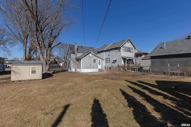 rear view of property with entry steps, an outdoor structure, a storage shed, and a lawn