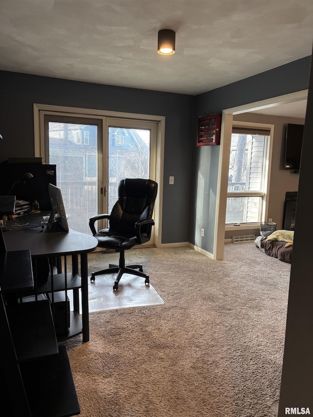 carpeted office space featuring a healthy amount of sunlight, visible vents, and baseboards