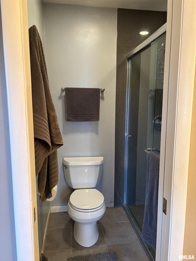 bathroom with toilet, a stall shower, and tile patterned floors