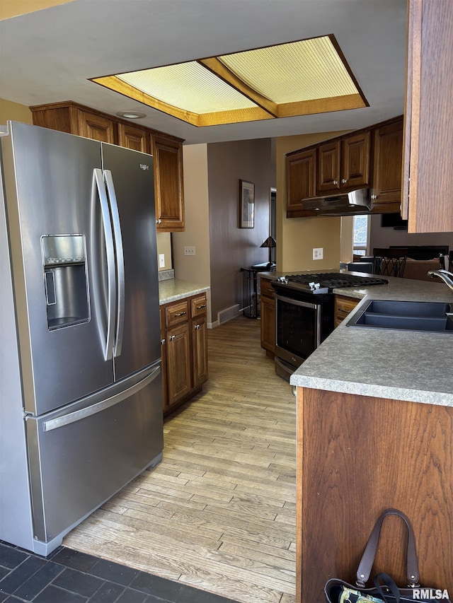 kitchen featuring light wood finished floors, visible vents, appliances with stainless steel finishes, a sink, and under cabinet range hood