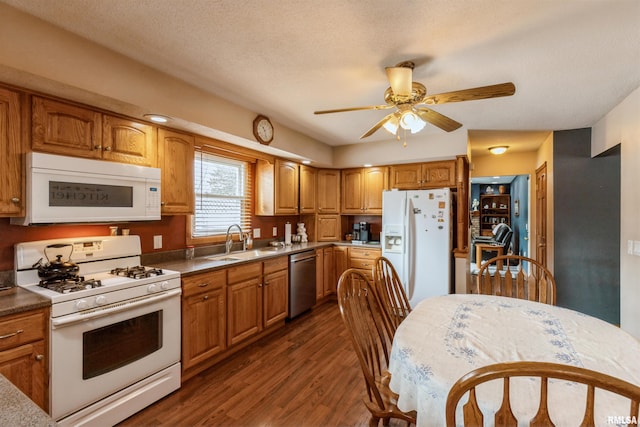 kitchen featuring dark wood-style floors, white appliances, a sink, and brown cabinets