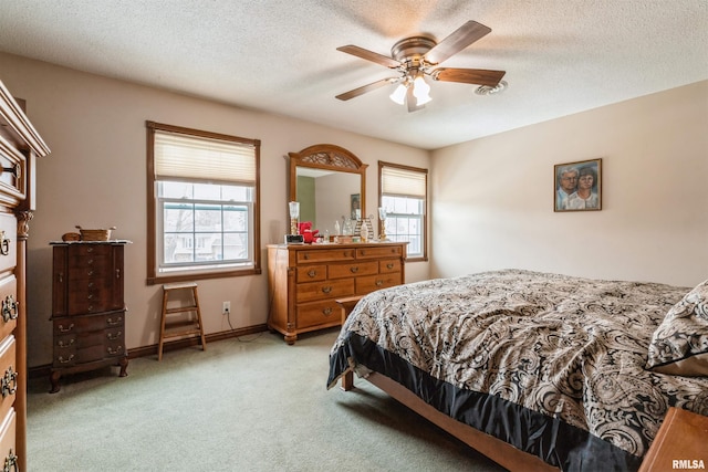 bedroom with a ceiling fan, light carpet, a textured ceiling, and baseboards