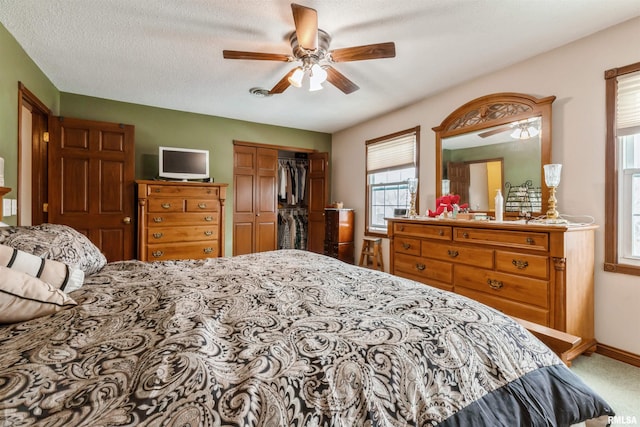 carpeted bedroom featuring a ceiling fan, a closet, a textured ceiling, and baseboards