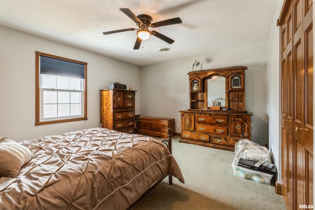 bedroom featuring a ceiling fan, carpet, a closet, and a textured ceiling