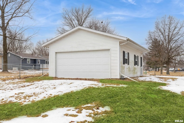 view of snowy exterior with a garage, a yard, fence, and an outbuilding