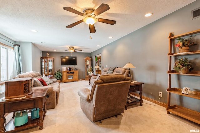 living area featuring baseboards, visible vents, a textured ceiling, and light colored carpet